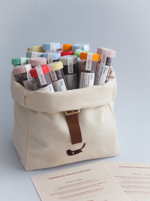 Calico Christmas Calendar 2026 with coffee tubes in the open canvas bag